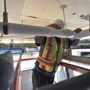 Man Fixing Overhead Corroded Pipe